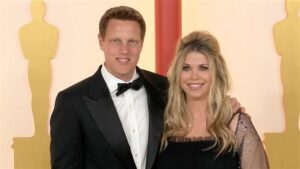 Portrait of Sandra Lynn Modic smiling outdoors in natural light, wearing casual attire with a blurred green background!!