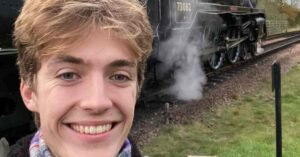 Francis Bourgeois smiling beside a passing train, representing his social media success and growing net worth