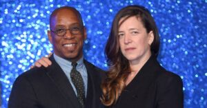 Nancy Hallam standing beside her husband during a community event, both looking confident and happy together.