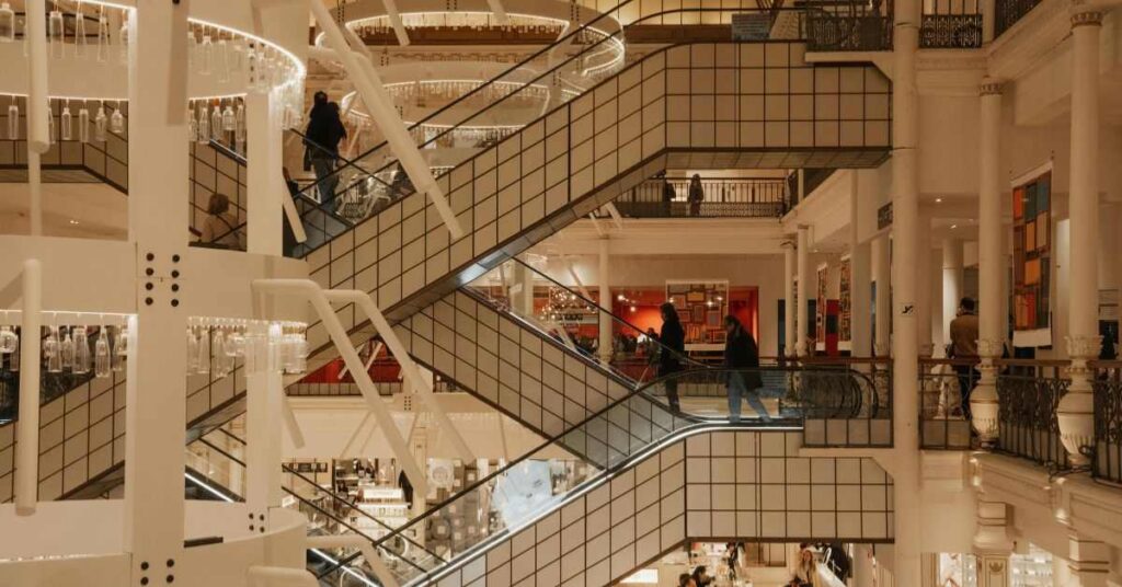 "Inside a modern multi-level shopping mall with people on escalators"