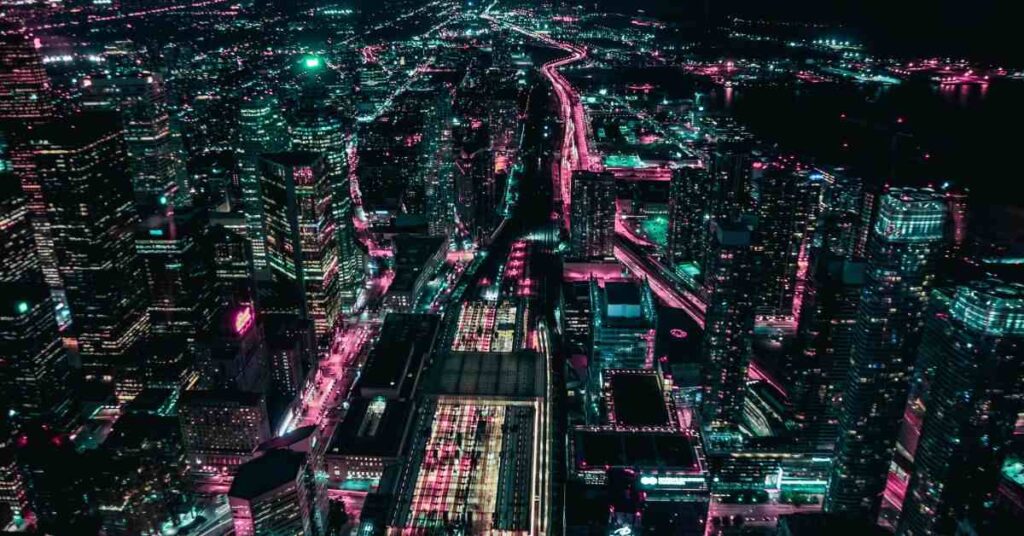 "Aerial view of a city at night with glowing neon lights and busy streets"